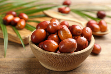 Palm oil fruits in bowl on wooden table, closeup