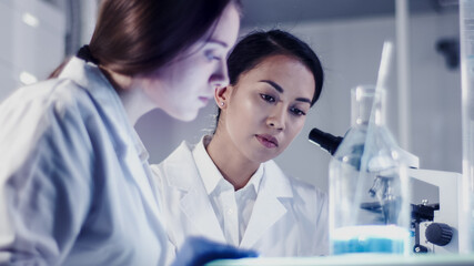 Modern laboratory. Female scientists working with microscope. Testing biohazardous samples
