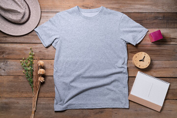 Mockup of a gray t-shirt blank shirt template with accessories on the wooden table background,...