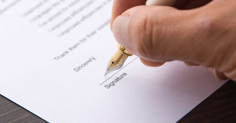 A hand signing a letter. Hand holding a pen and signing a document.