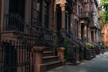 Row of Beautiful Old Brownstone Homes with Staircases along a Sidewalk in Greenwich Village of New York City