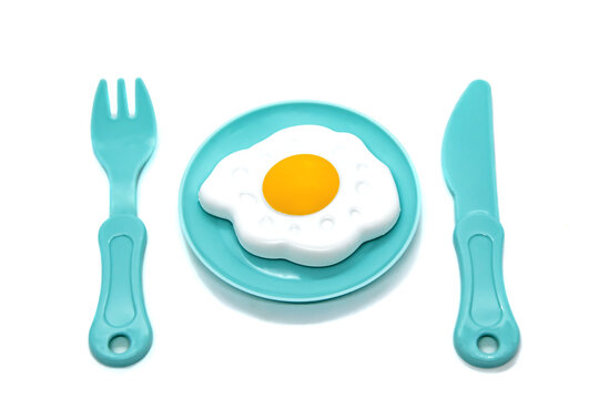 Children's toy plastic tableware: plate with fried eggs, fork and knife. Serving set. Developing role-playing games for children. Kitchen utensils, household training. Kid's Kitchen.