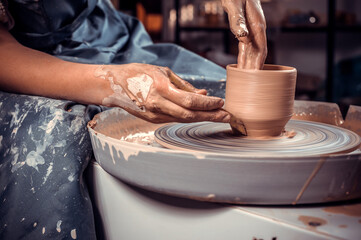 Hands of the master potter and vase of clay on the potter's wheel close-up. Master crock. Twisted potter's wheel.