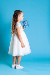 a full-length girl in a white dress stands sideways and holds a Giftbox for a Christmas party...