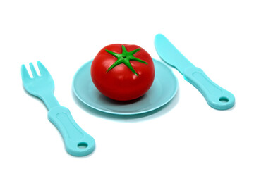 Children's toy plastic tableware: plate with tomato, fork and knife. Serving set. Developing role-playing games for children. Kitchen utensils, household training. Kid's Kitchen.