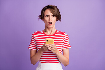 Photo of confused mad young lady hold smartphone offended face wear striped t-shirt isolated violet color background