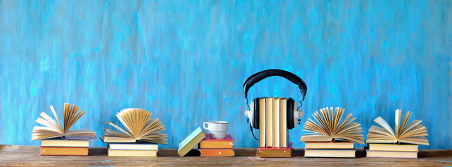 audio book concept with open books, cup of coffee, and vintage headphones, panoramic, good copy...