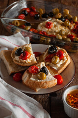 Bruschetta with baked cheese, cherry tomatoes, olives, herbs and butter