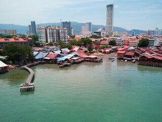 Drone view of historic homes on the water (clan jetties) and modern George Town. The island of Penang, Malaysia.