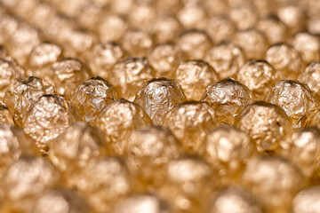 a lot of round candy wrapped in gold foil closeup