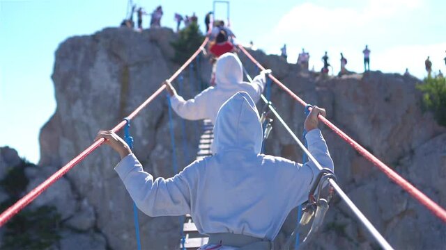 Girls crossing the chasm on the rope bridge. Black sea background, Crimea