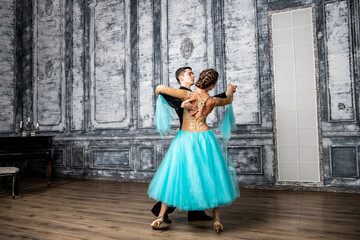 a young man in a black suit is dancing with a girl in a turquoise dress in the dance hall