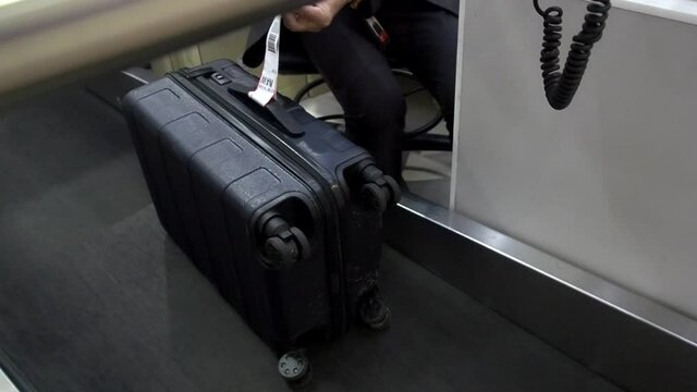 airline ground staff attach check in baggage tag on trolley bag at check-in counter.
