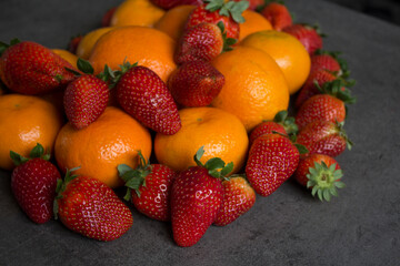 Strawberries and oranges on dark grey background. Fruits top view photo.  Fruit diet concept. 