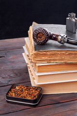 Books and pipe smoking accessories. Vertical shot still life composition.