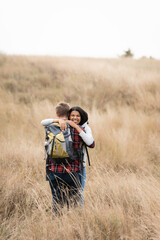 Cheerful african american traveler embracing boyfriend on hill with grass