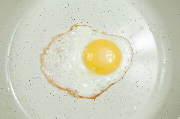fried chicken egg in a white frying pan top view