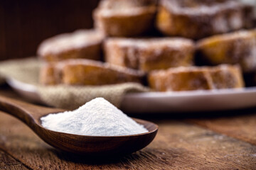 wooden spoon with refined sugar on the side, rustic kitchen concept. Spot focus, toast in the background