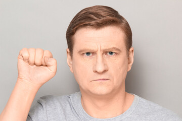 Fototapeta premium Portrait of rebellious confident mature man raising fist up