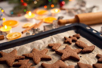 Baking tray with tasty fresh still warm biscuits on a table with some Christmas decorations on the background. Christmas holiday preparations