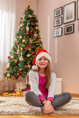 Obraz na płótnie Canvas Little girl wearing Santa hat celebrating Christmas at home