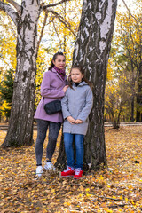 Naklejka na ściany i meble mother and daughter walking in the autumn park. vertical photo