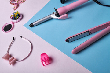 Pink womens beauty accessories. Top view hair straighteners and other stuff.
