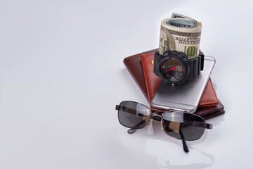 Stack of mens stuff isolated on white. Handwatch with money and sunglasses.