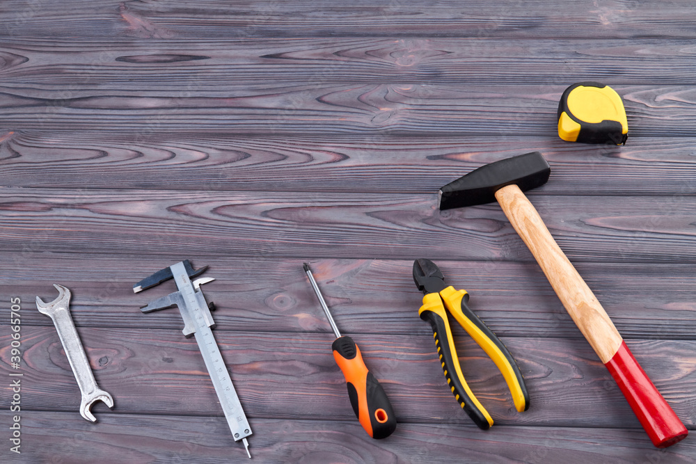 Wall mural Tools set on grey wooden background. Top view hammer pliers scredriver and wrench on wood.