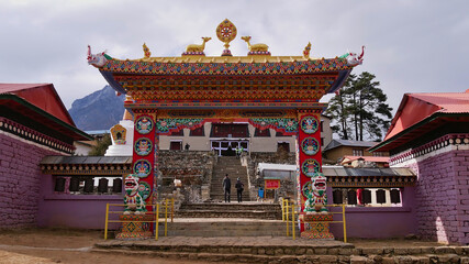 Naklejka premium Front view of popular historic monastery (Buddhist gompa) of Thyangboche (Tengboche) with colorful ornate entrance gate, religious decorations and prayer wheels in Khumbu region, Himalayas, Nepal.