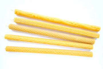 Large yellow candles with different cut patterns on white. Lie side by side, top view