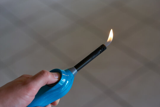 Aktiviertes Feuerzeug mit kleiner Flamme in Hand