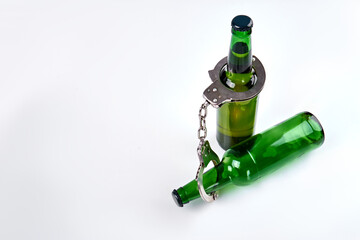 No alcohol law concept. Top view two green bottles with handcuffs isolated on white background.