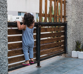 Caucasian girl  trying to look over the fence - the concept of curiosity