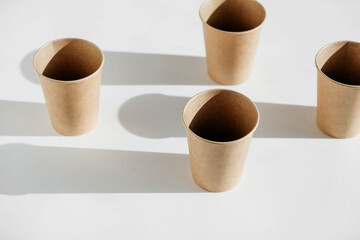 Disposable paper cups with shadow from light on white background. Copy, empty space for text