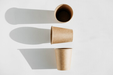 Three disposable paper cup with shadow from light on a white background. Top view. Copy, empty space for text