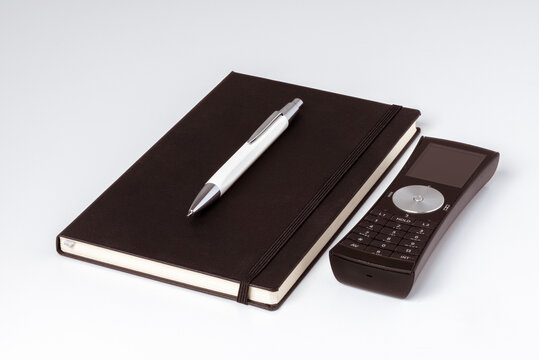 Carnet de note noir avec un stylo et un téléphone posés