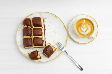 Homemade chocolate pie cheesecake and cup of coffee cappuccino on white wooden table. Top view.