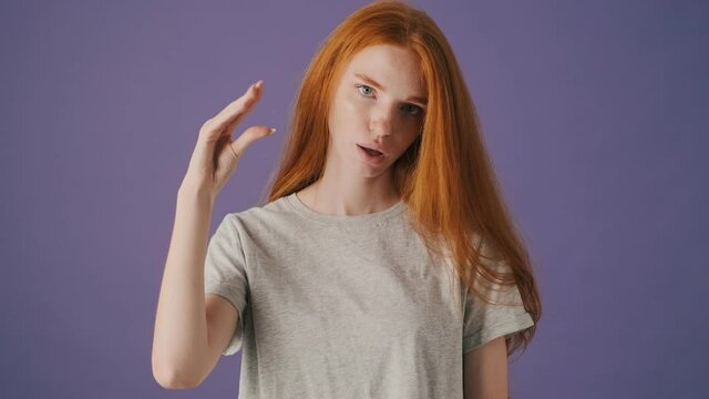 A bored young woman is doing blablabla gesture standing isolated over a violet background