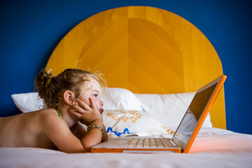 3 year old girl looking at laptop in hotel room