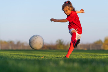 Fototapeta Little girl kicks soccer ball obraz