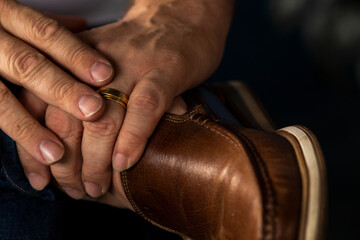 Brown leather shoe and man's hand with engagement gold rind
