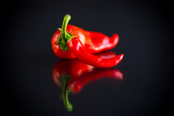 two hot spicy cayenne peppers on black background