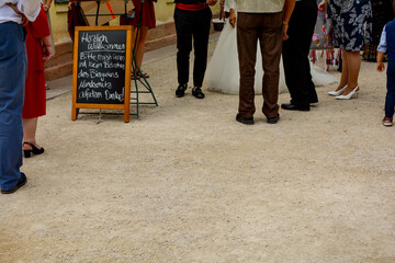 Fototapeta premium Sign for mandatory masking in the beer garden with many legs of people