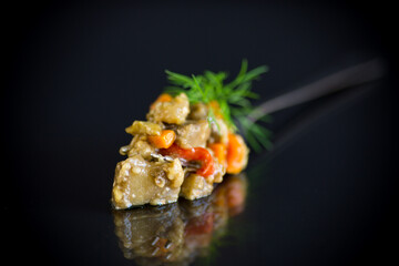 cooked summer eggplant caviar with vegetables on black background