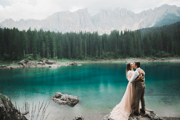 Beautiful modern couple kissing near a lake in the mountains