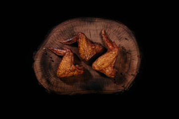 Three smoked fragrant juicy chicken wings on a wooden board. Top view.