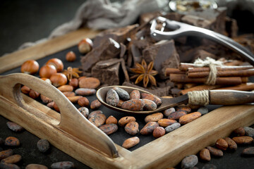 Dark chocolate in a composition with cocoa beans and nuts, on an old background.