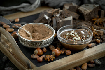 Dark chocolate in a composition with cocoa beans and nuts, on an old background.