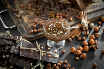 Dark chocolate in a composition with cocoa beans and nuts, on an old background.